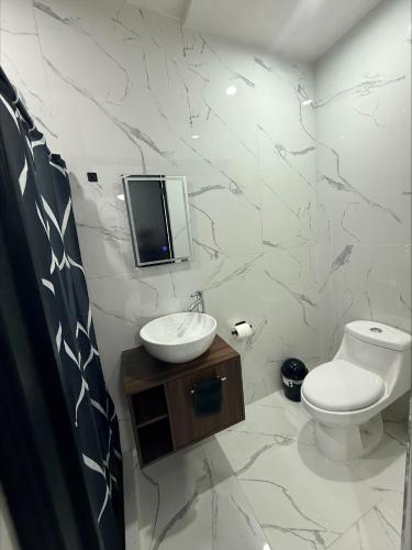 a bathroom with a toilet and a sink and a mirror at Lujoso departamento con alberca y jacuzzi in Monterrey
