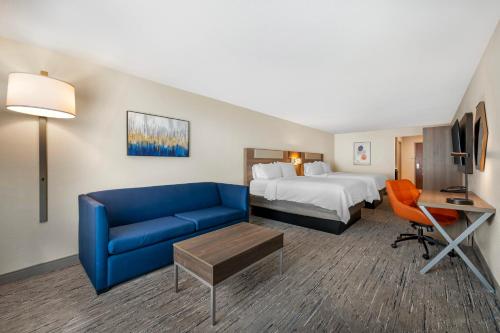 a hotel room with a bed and a blue couch at Holiday Inn Express Selinsgrove by IHG in Shamokin Dam