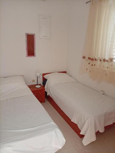 two beds in a room with white sheets and a window at Dobrila in Slano