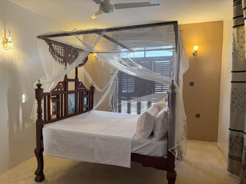 a bedroom with a canopy bed with white sheets and pillows at Bakarani in Mombasa
