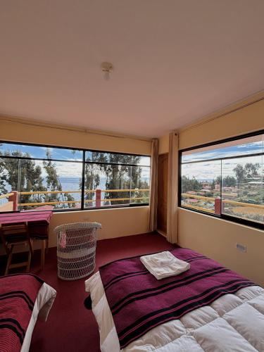 a bedroom with two beds and a table and windows at Musqoy Wasi de Gonzalo in Ocosuyo