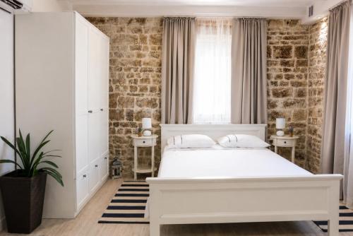 a bedroom with a white bed and a brick wall at Trogir Square Apartment in Trogir