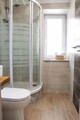 a bathroom with a shower and a toilet and a window at Trogir Square Apartment in Trogir