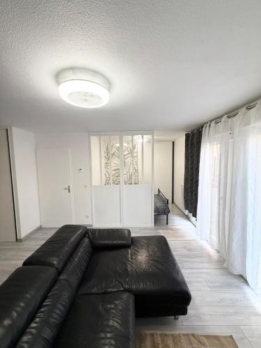 a living room with a black leather couch at Large studio Independent sleeping area Swimming pool in Annemasse