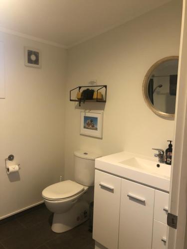 a bathroom with a white toilet and a sink at Ocean Cliff Court in Kuaotunu