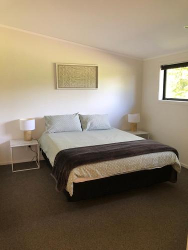 a bedroom with a bed with two tables and two lamps at Ocean Cliff Court in Kuaotunu