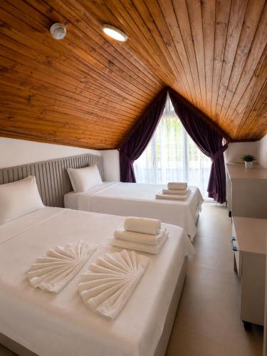 two beds in a room with a wooden ceiling at The Selection Butik Otel in Kemer