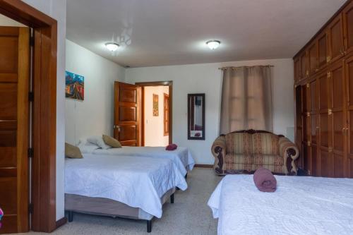 a bedroom with two beds and a chair in it at House antigua Guatemala in Antigua Guatemala