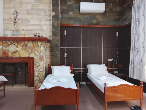 two beds in a room with a fireplace at Guest House Univers in Berat