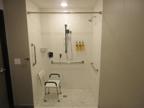 a bathroom with a shower with a chair in it at Glo Best Western Olive Branch in Olive Branch