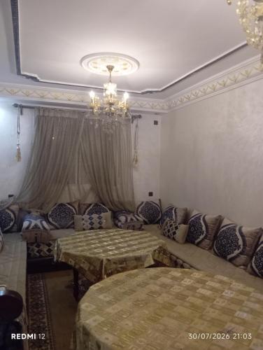 a room with two beds and a couch and a chandelier at Rez de chaussée in Ifrane