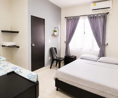 a bedroom with a bed and a chair and a window at Hostal Mi Puerto in Puerto Triunfo