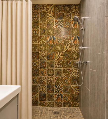 a bathroom with a shower with a tiled wall at KUBU Loft in Klaipėda