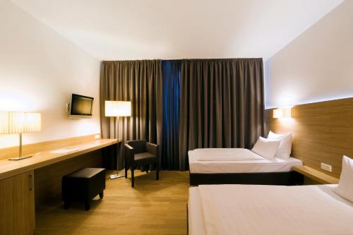 a hotel room with two beds and a desk at Hotel Thalmair in Munich