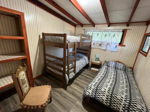 a room with two bunk beds and a chair at Cabañas Rayen Lemu in Panguipulli