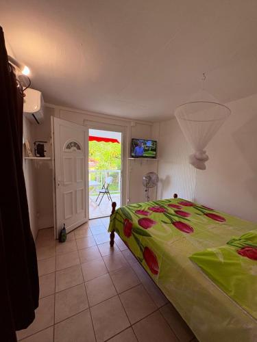 a bedroom with a bed with a green comforter at Studio Arawak in Deshaies