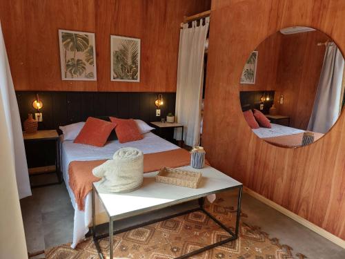a bedroom with a bed with a mirror and a table at Madera y sal Cabañas piriapolis in Playa Hermosa