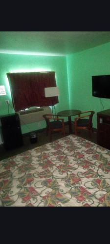 a green room with a bed and a piano at Capital Motel in Columbus