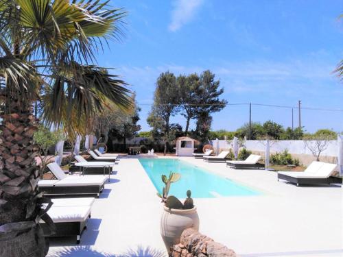 a swimming pool with chaise lounge chairs and palm trees at Hotel Residence Noto Marina Relais in Calabernardo