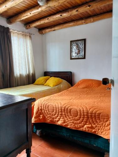 two beds in a room with wooden ceilings at Hospedaje Patty Cajicá in Cajicá