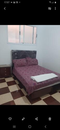 a bedroom with a bed with a red comforter at agadir location vacance aourir plage in Aourir