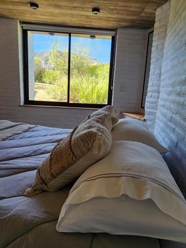 a bedroom with a large bed with pillows and a window at La Choza - Refugio para dos in La Falda
