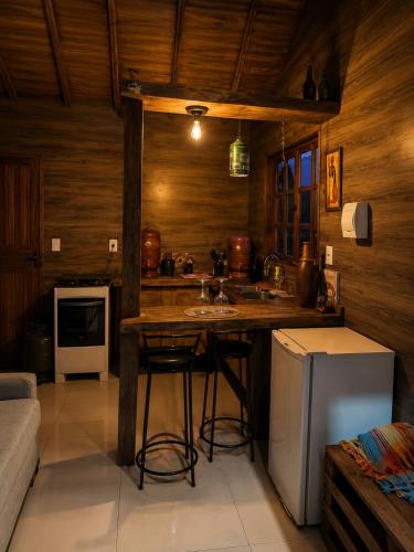 a kitchen with a counter with a sink and a refrigerator at Chalé Recanto da Cuesta in Botucatu