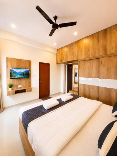 a bedroom with a large bed with a ceiling fan at Sai Grand Villas & Hotel Near Bengaluru Airport in Bangalore