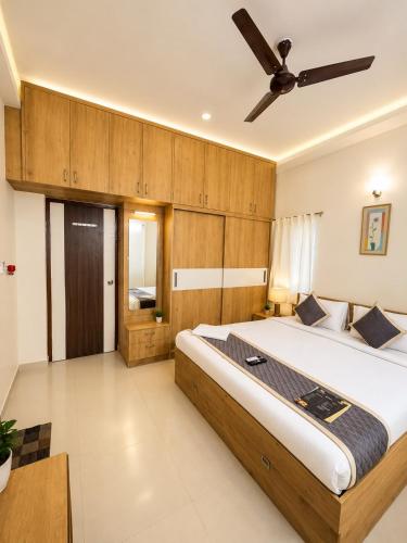 a bedroom with a large bed with a ceiling fan at Sai Grand Villas & Hotel Near Bengaluru Airport in Bangalore