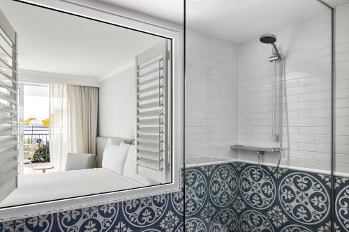 a bathroom with a mirror and a bath tub at The Beachcomber Hotel & Resort in Toukley