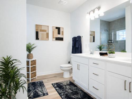 a white bathroom with a toilet and a sink at The Palm LK Private Beach Club 100"TV in Pensacola