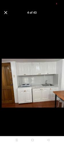 a kitchen with white cabinets and a wooden table at Jenny's accomodation in Baguio