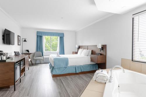 a hotel room with a bed and a bath tub at Ramada by Wyndham Surrey/Langley in Langley