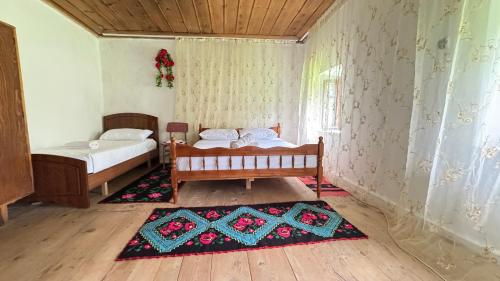 a bedroom with two beds and a rug at Kulla e Vjetër ,Vermosh in Vermosh