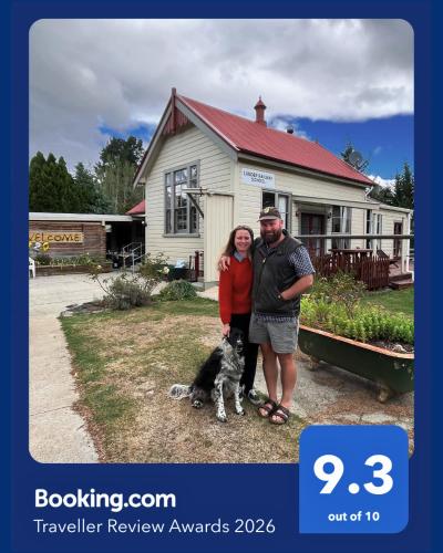 a man and woman standing in front of a house with a dog at Lauder School Bed & Breakfast in Lauder