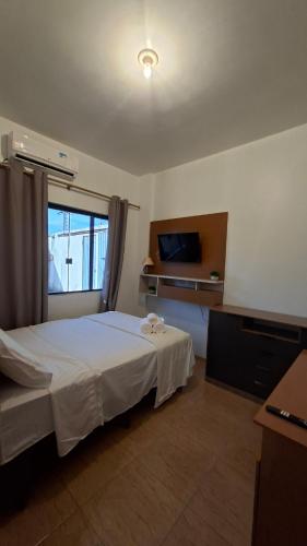 a bedroom with a white bed and a window at Studio Executivo Completo com Garagem , Ar e Wi-fi in Parauapebas