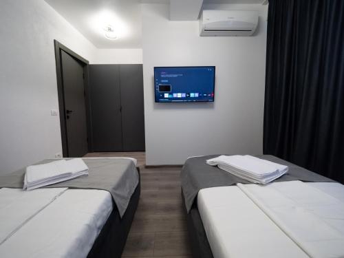 two beds in a room with a tv on the wall at NORTH GATE Rooms in Afumaţi