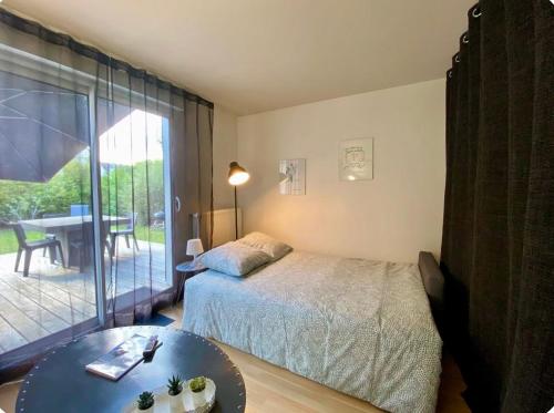 a bedroom with a bed and a table and a patio at Independent studio - Cicé Blossac Golf in Bruz