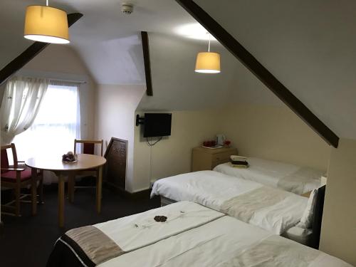 Habitación con 2 camas, mesa y ventana en A Gosport Inn, en Gosport