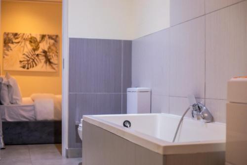 a bathroom with a sink and a toilet and a bed at Beaufort Ridge - Skysuites in Accra