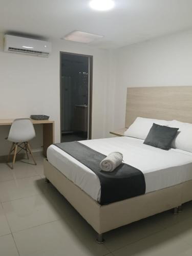 a bedroom with a large white bed and a desk at Hotel pasarela real cali in Cali
