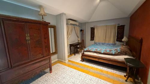 a bedroom with a bed and a large wooden cabinet at Cozy two-storey home in Ban Lam Praya Phai Rua