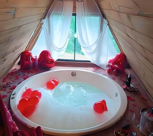 a bath tub in a tent with red chairs in it at Imperatriz Cabanas (Chalé 1 com hidromassagem) in Santo Amaro da Imperatriz