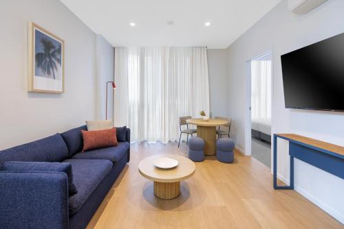 a living room with a blue couch and a tv at Quest Southport in Gold Coast