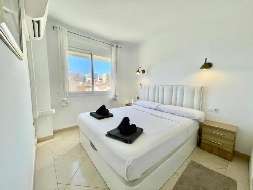 a white bedroom with a bed with black towels on it at Apartamento El Nido in Torre del Mar