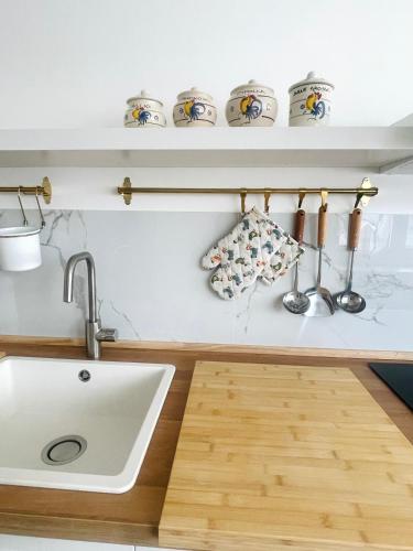 a kitchen with a sink and a shelf with cups at Apuliantales Cottage Bari in Carbonara di Bari