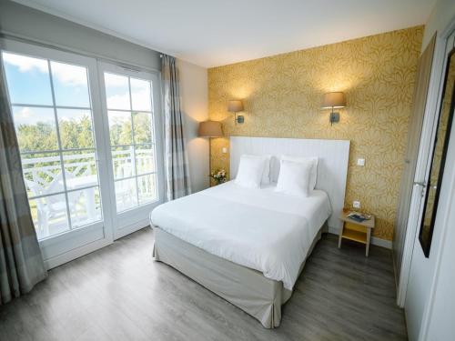 a bedroom with a white bed and a large window at Tranquil Apartment with Pool Access in Bagnoles de l'Orne