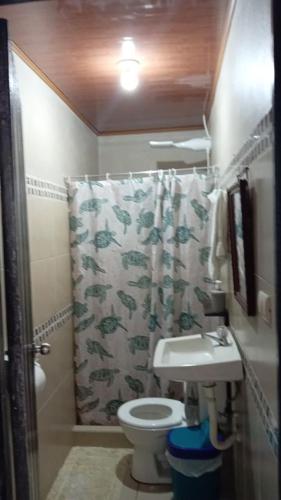 a bathroom with a toilet and a shower curtain at Apartamentos Caimán Tortuguero in Tortuguero