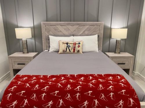 a bedroom with a bed with a red blanket and two lamps at Loon Resort Condo-AC, Pool, Hot Tub and Views in Lincoln