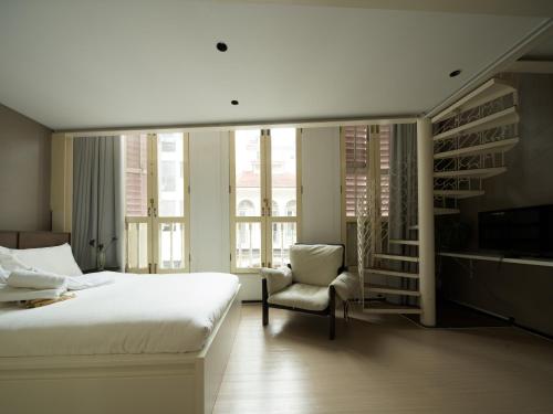 a bedroom with a bed and a chair and a tv at Aura Hotel Purvis in Singapore